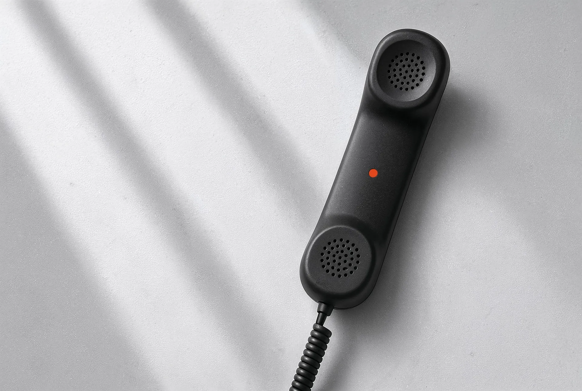 Ein schwarzer Telefonhörer im Fensterlicht